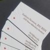 Photo shows 4 business cards fanned out. They are a business card for a midwifery student. There is an image of a silhouette of a woman, with a red heart where the uterus/fetus would be.
